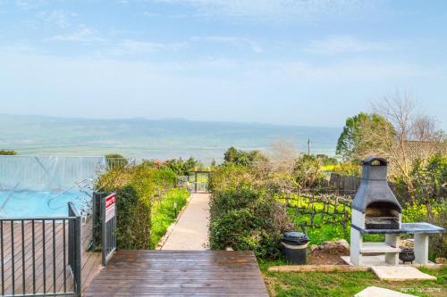 a wooden boardwalk leading to a garden with a grill at Vibe Naftali Estate in Ramot Naftali