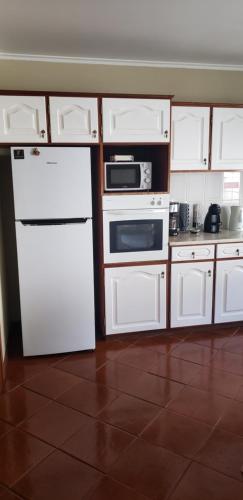 a kitchen with white appliances and white cabinets at Casa da Ribeira in Povoação