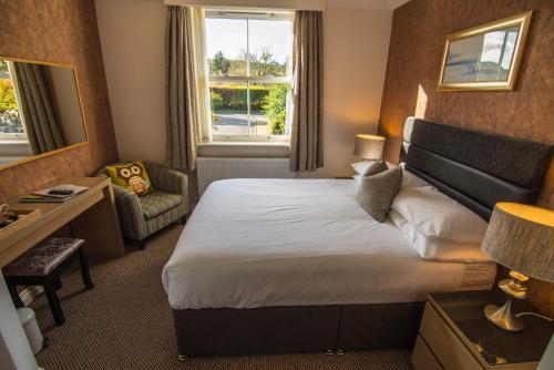 um quarto de hotel com uma cama grande e uma cadeira em Owlswood Apartments em Edinbain