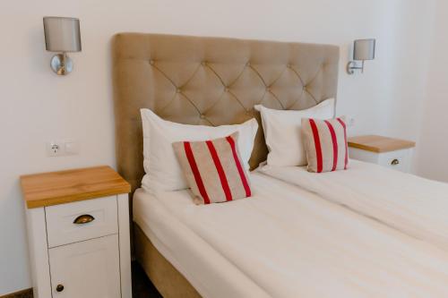 a bedroom with a large white bed with red and white pillows at La Fontaine in Hunedoara