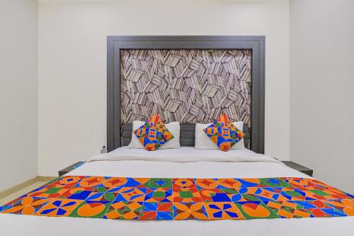 Una cama con una manta colorida y almohadas. en FabExpress Pearl Villa, en Ahmedabad