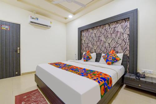 1 dormitorio con 1 cama blanca grande con almohadas coloridas en FabExpress Pearl Villa, en Ahmedabad