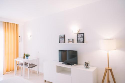 a white living room with a television and a table at Apartamento Añoreta Malaga 318 in Torre de Benagalbón