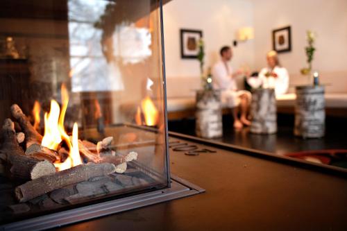 a fire in a fireplace with two people in the background at Åkerblads Hotell Gästgiveri Spa in Tällberg