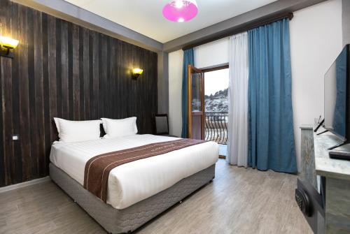 a bedroom with a large bed and a balcony at Alaska Resort in Tsaghkadzor