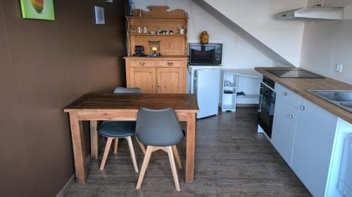eine Küche mit einem Holztisch und 2 Stühlen in der Unterkunft Mini Happy home in Reconvilier