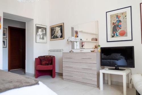 sypialnia z komodą z telewizorem i czerwonym krzesłem w obiekcie Casa Andromaca w mieście Noto
