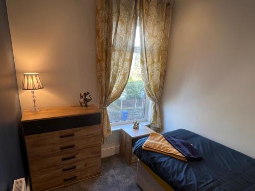 a bedroom with a bed and a dresser and a window at Luxury 2 bed Apartment in Stoke-on-Trent in Stoke on Trent
