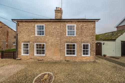 a brick house with white windows and a driveway at The Town House in Woodbridge