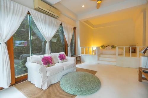 a living room with a white chair and a large window at Proud Phu Fah Maerim Resort in Mae Rim
