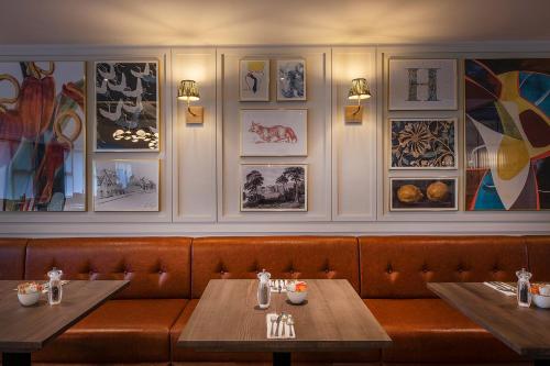 a restaurant with two tables and pictures on the wall at Horwood House Hotel in Milton Keynes