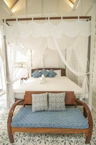 a bedroom with a canopy bed with a bench at Proud Phu Fah Maerim Resort in Mae Rim