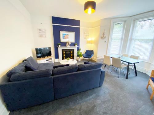 a living room with a blue couch and a table at Sail Away. 1-Bed apartment close to the beach in Bournemouth