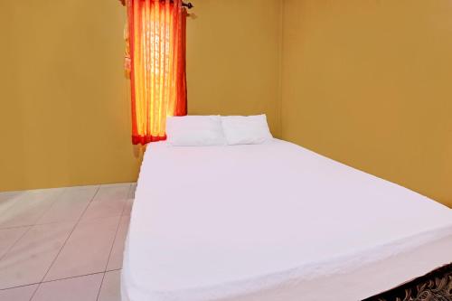 OYO 92142 Ujung Samalas Homestay في لومبوك: غرفة نوم بسرير ابيض ونافذة برتقالية