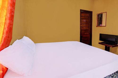 a bedroom with a white bed and a television at Hotel O Ujung Samalas HomestayNearLapangan Sembalun Bumbung in Labuan Lombok