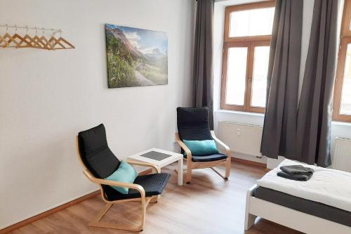Zimmer mit 2 Stühlen, einem Bett und Fenstern in der Unterkunft Cozy 2 Room Apartment in Magdeburg in Magdeburg