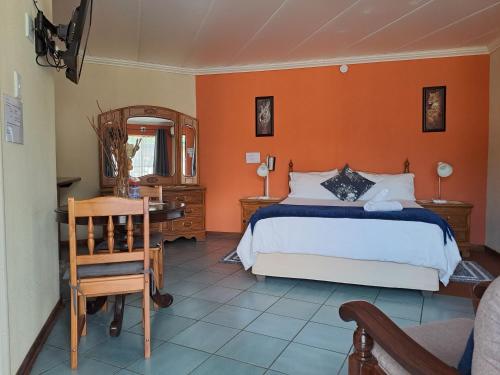 a bedroom with a bed and a desk and a chair at Amigos Bed & Breakfast - No loadshedding in Nelspruit