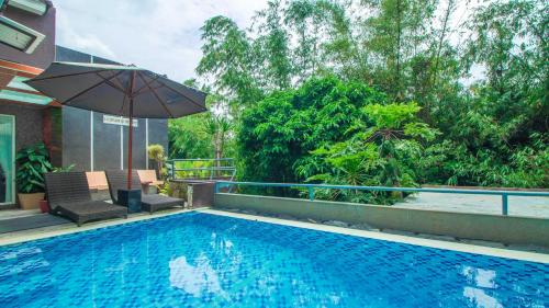 una piscina con sombrilla junto a una casa en Villa Dewata with Chill Spot Private Pool and Karaoke, en Batu