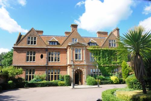 a large brick house with a palm tree in front of it at Horwood House Hotel in Milton Keynes