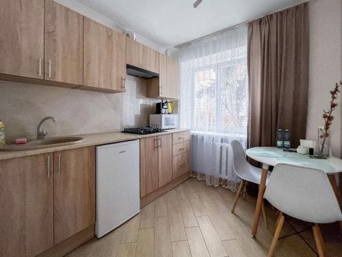 a kitchen with wooden cabinets and a small table with a white refrigerator at Апартаменти по вул Галицька in Ivano-Frankivsʼk