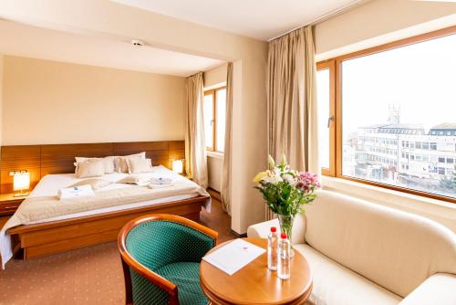 VratsaにあるHemus Hotel - Vratzaのベッド、テーブル、椅子が備わるホテルルームです。