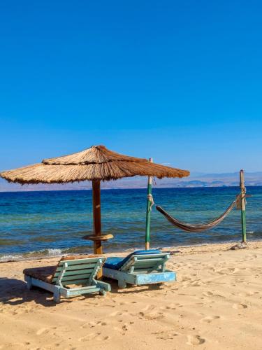 two chairs and an umbrella on a beach at Baraka Camp in Taba