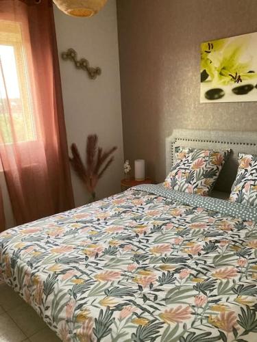 une chambre avec un lit avec une couette fleurie dans l'établissement Maison Chante Vigne, à Saint-Maximin-la-Sainte-Baume