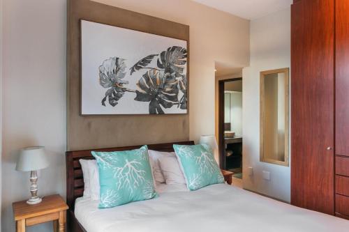 Pezula Sunset Views في كنيسنا: غرفة نوم مع سرير ووسائد زرقاء وبيضاء