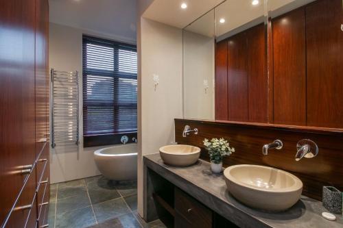 Pezula Sunset Views في كنيسنا: حمام به مغسلتين ومرآة كبيرة