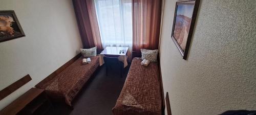 a room with two beds and a table and a window at Мотель ОК in Shepetivka