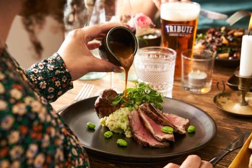 a person is pouring sauce onto a plate of food at Havener's in Fowey