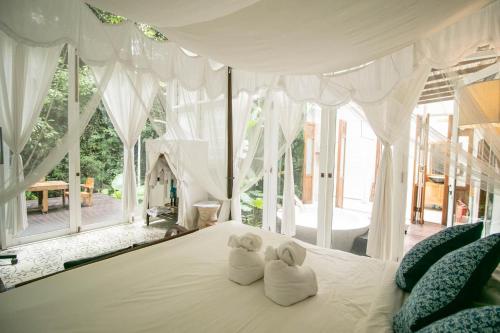 two towels on a bed in a room with windows at Proud Phu Fah Maerim Resort in Mae Rim