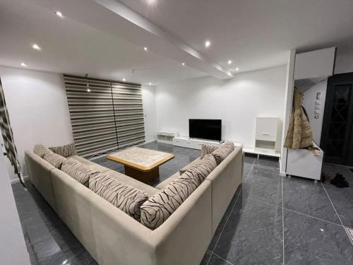 a living room with a large couch and a tv at Soleil de bois d’amont in Bois-dʼAmont