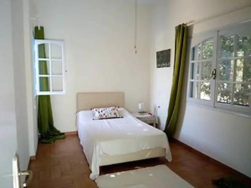 a bedroom with a white bed and a window at VILLA KANTOUNI ON THE BEACH in Panormos Kalymnos