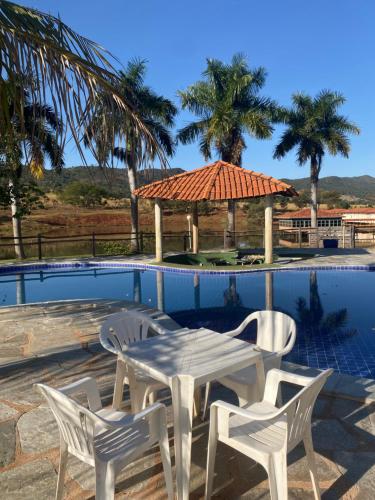 einen weißen Tisch und Stühle neben einem Pool in der Unterkunft Hotel Fazenda Pousada da Serra in Goianésia