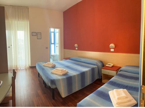 1 dormitorio con 2 camas y pared roja en Hotel Senior, en Cattolica