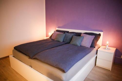 a bedroom with a large bed with a purple wall at 2 Zimmer mit Netflix, Prime, Küche, Bad in Seenähe in Unterwellenborn