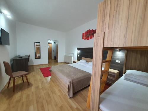 Hotel Mures في توبليتا: غرفة نوم بسريرين ومكتب وكرسي