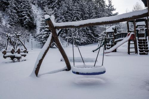 a playground covered in snow with a swing at Stará Zvonica in Nižná Boca