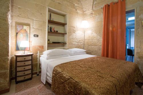 1 dormitorio con 1 cama en una pared de piedra en B&B Corte Dei Musco, en Lecce