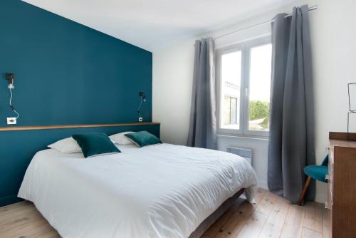 a bedroom with a large bed with a blue wall at Villa Piscine tout confort in La Flotte