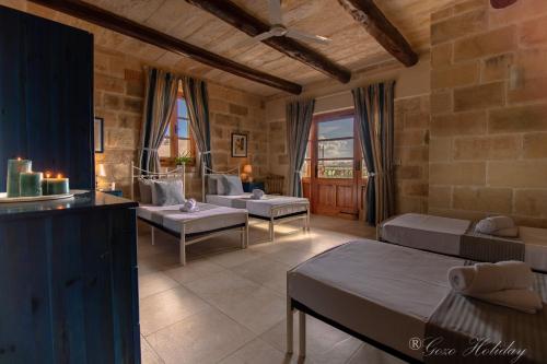 a living room with two beds and a table at Tan-Nanna Holiday Home in Xagħra