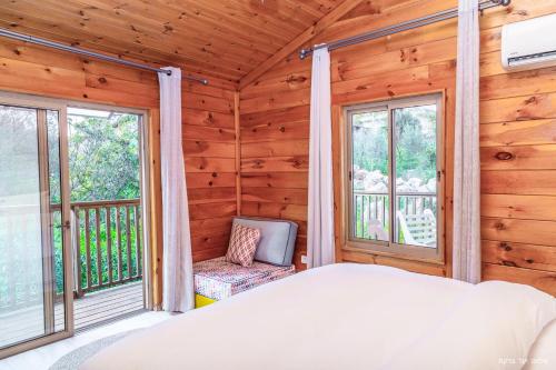 a bedroom with a bed and windows in a log cabin at Vibe Naftali Estate in Ramot Naftali