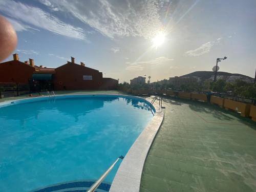 a large swimming pool with the sun in the sky at Simon beach house Los Cristianos in Los Cristianos
