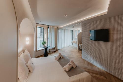 テラサにあるHotel Petit Luxeのベッドとテレビが備わるホテルルームです。