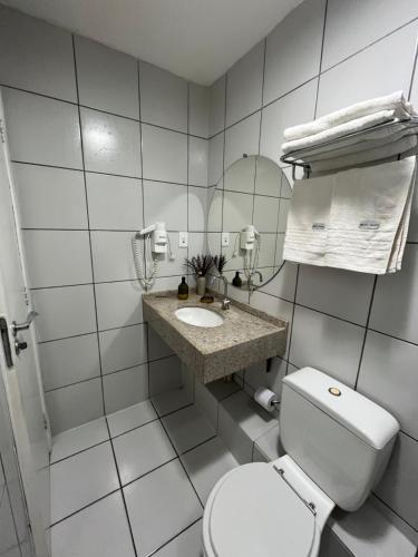 a white bathroom with a toilet and a sink at Gran Lençóis Flat Apartamento in Barreirinhas