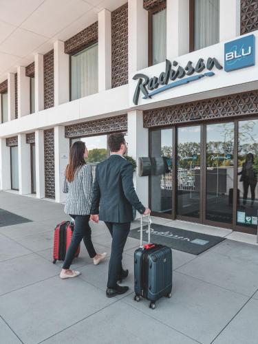 a man and a woman walking with their luggage at Radisson Blu Hotel, Bruges in Bruges