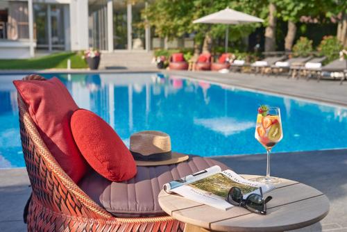 een tafel met een hoed en een wijnglas naast een zwembad bij Normafa Hotel in Boedapest