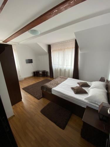 a bedroom with a large bed and wooden floors at Pensiunea Cristiion in Măţău