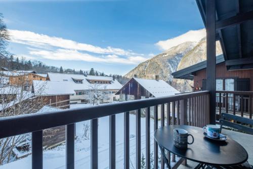 uma varanda com uma mesa e vista para as montanhas em Apt with nice view near the center of Chamonix em Chamonix-Mont-Blanc